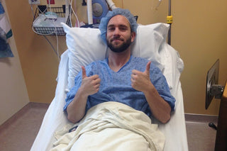 Man in a hospital bed giving two thumbs up
