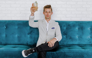 Man holding a drink while seated on a blue couch