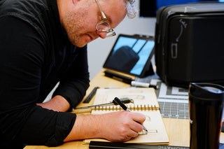 Designer sketching luggage concepts beside a black suitcase