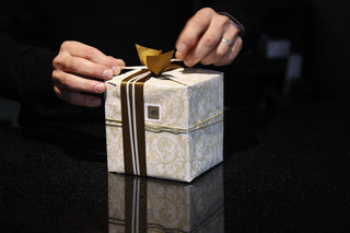 Hands wrapping a gift box with a ribbon