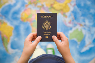 Hands holding a United States passport over a world map