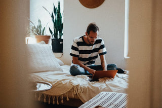 Man using a laptop while sitting on a bed