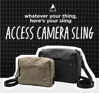 Two crossbody camera bags from Access Camera Sling are displayed against a black and white grid background with promotional text. The foreground bag is a solid taupe-beige color, and the background bag is a black and white micro-check pattern.