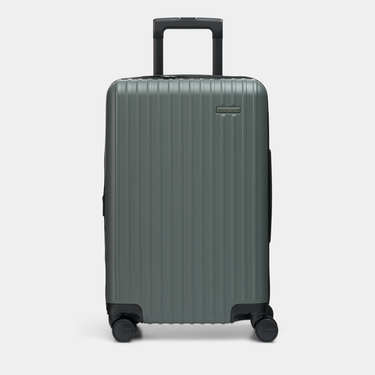 NOMATIC Method Carry-On in Moss with a ribbed hard shell, telescoping handle, and four spinner wheels.