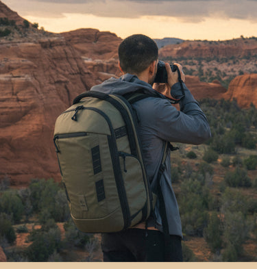 Photographer wearing a NOMATIC camera backpack while shooting a rugged red rock landscape.