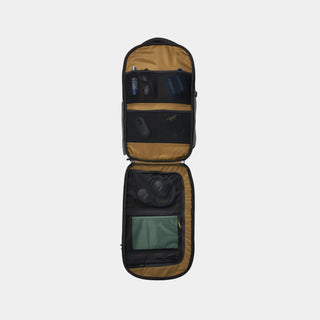 An open laptop backpack shown from a top-down view, displaying its interior organization with multiple compartments, mesh pockets, and padded headphone storage on a white background.
