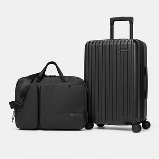 A black Nomatic luggage set featuring a hardshell spinner suitcase and a matching softside duffel bag, both with telescoping handles, shown on a light gray studio background.